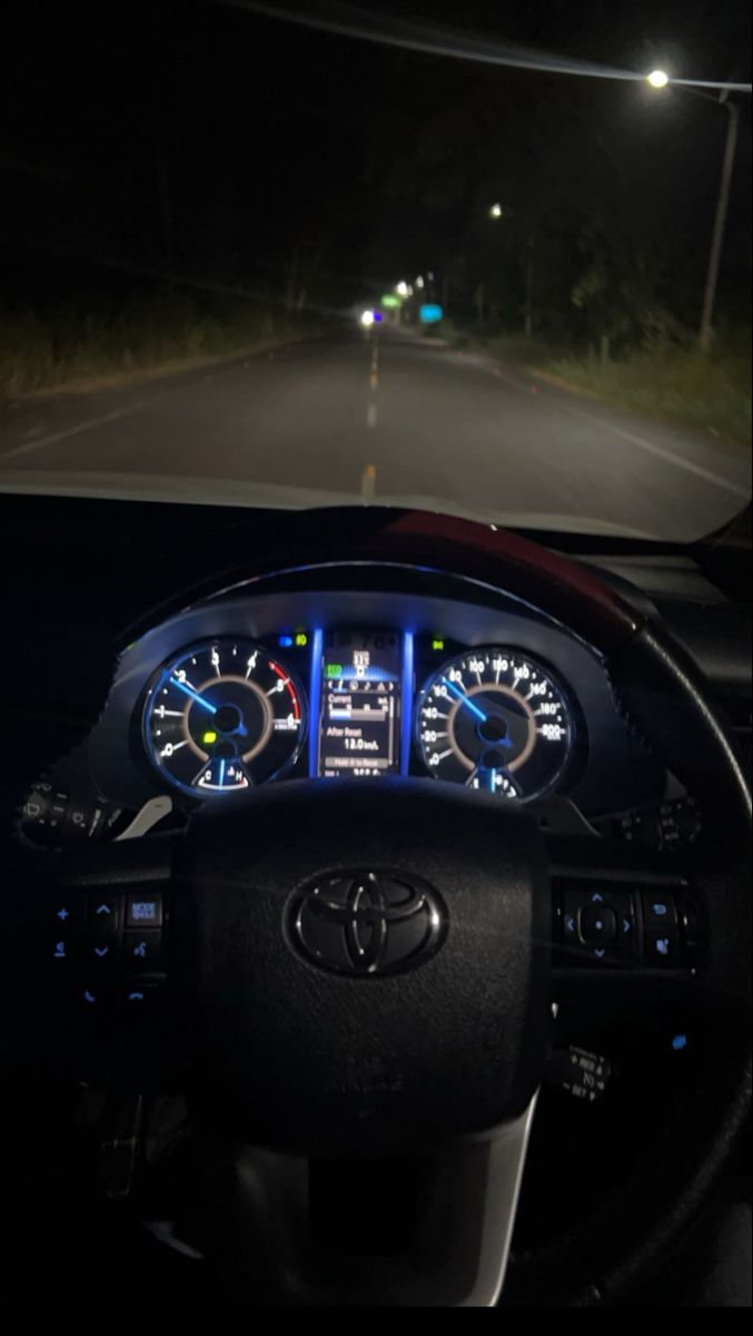 the dashboard of a car at night with its lights on and dash lights lit up