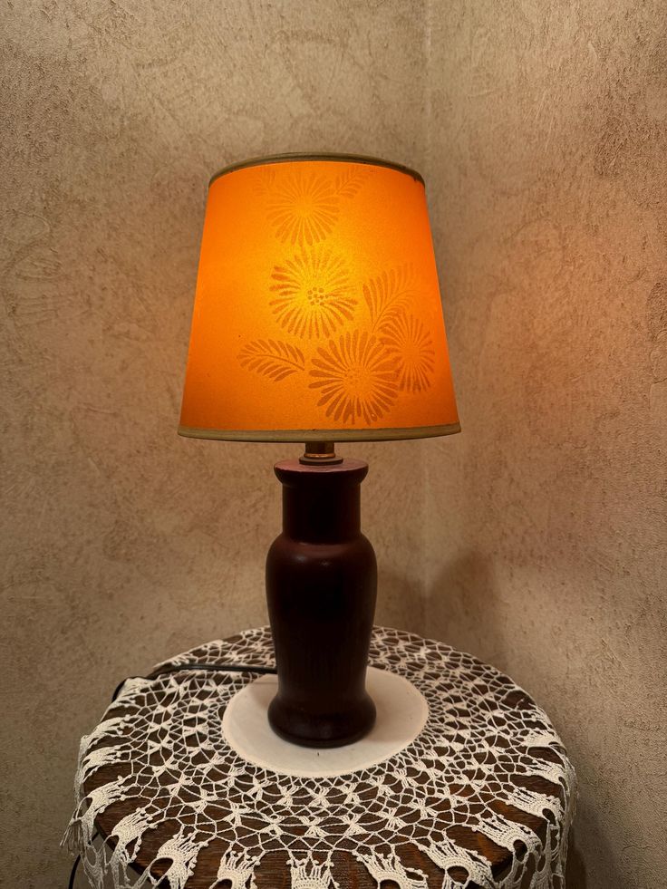 a lamp that is sitting on top of a table next to a wallpapered surface