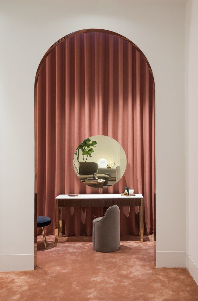 a room with red curtains and a desk in front of a mirror that has a potted plant on it