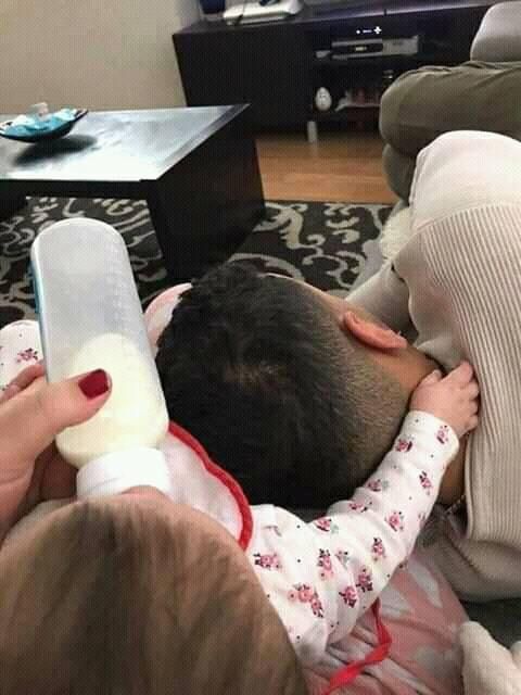 a woman laying on top of a couch next to a baby