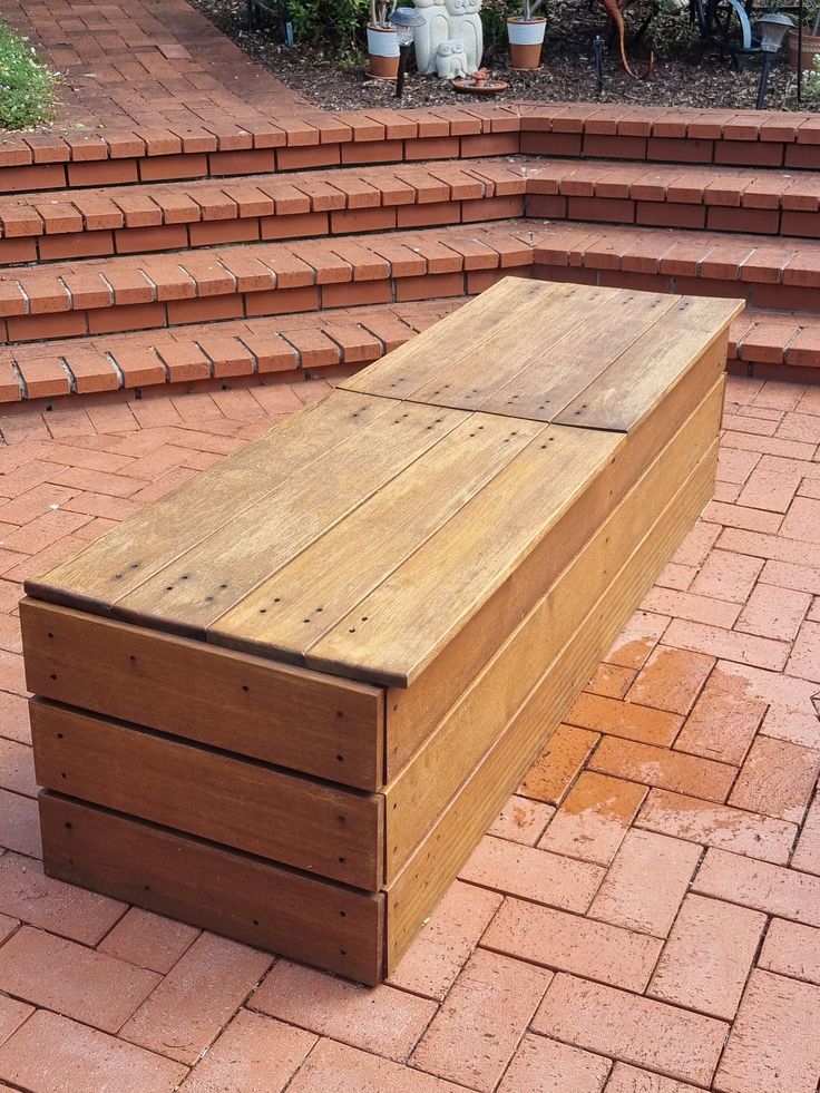 a wooden bench sitting on top of a red brick patio next to steps and plants