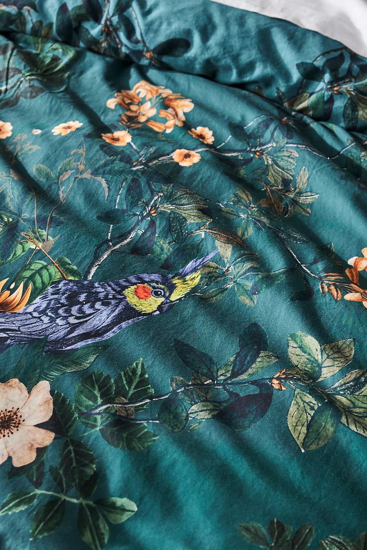 a bird is sitting on a tree branch in the middle of a floral print bed spread