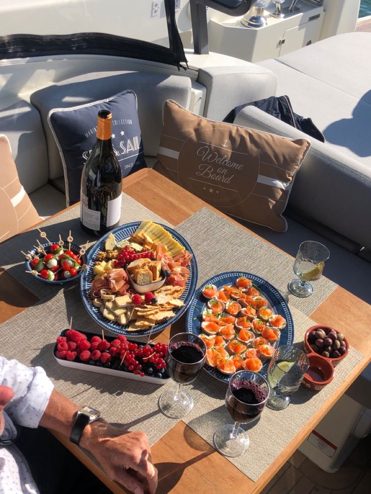 a man sitting at a table with plates of food on it and wine in front of him