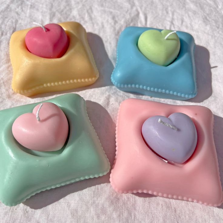 four small heart shaped soaps sitting on top of a white cloth covered tablecloth