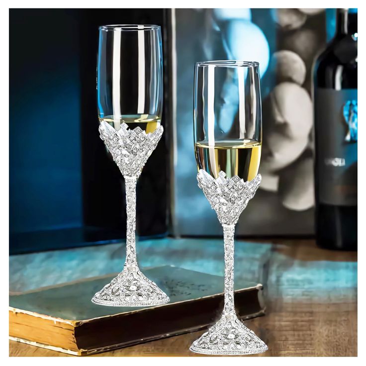 two wine glasses sitting on top of a table next to a book and glass bottle