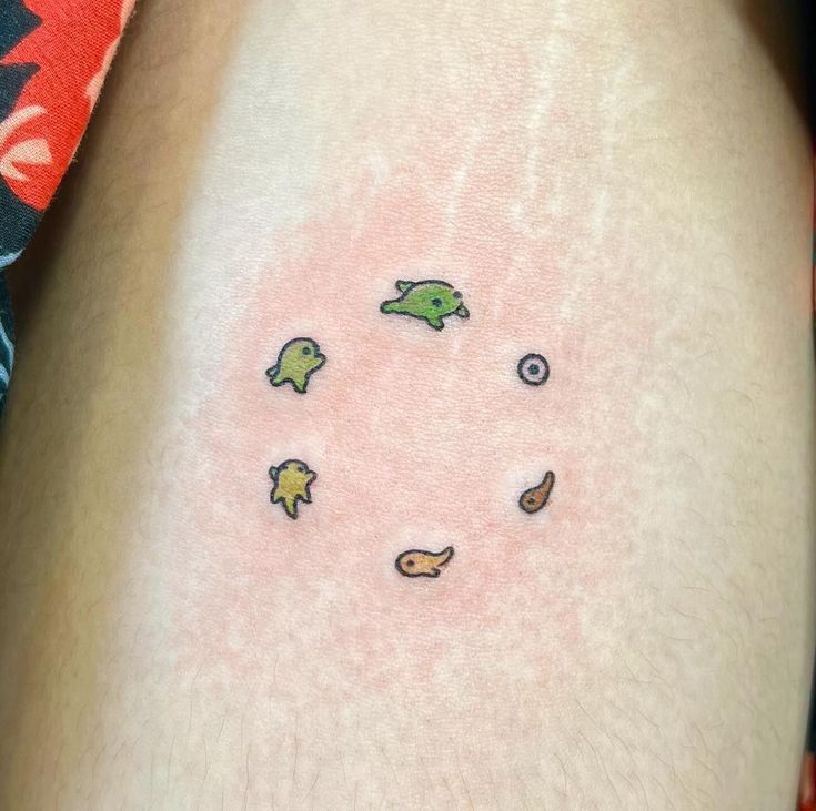 a small tattoo on the leg of a person's thigh, with an image of fish