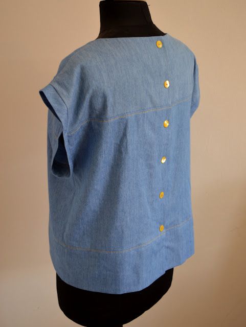 a mannequin is wearing a blue shirt with gold buttons on the front and back