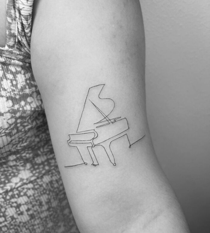 a black and white photo of a woman's arm with a piano tattoo