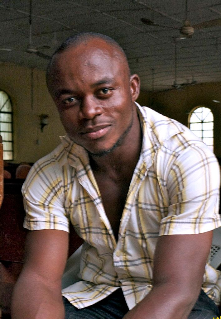 a man sitting on the floor in front of a table holding a cell phone and looking at the camera