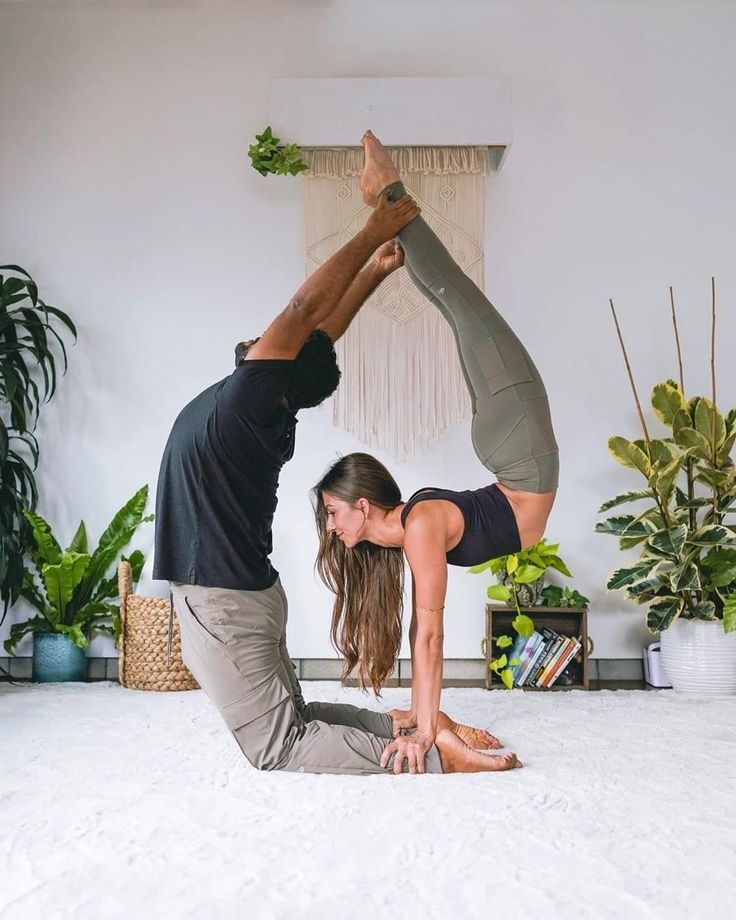 a man and woman are doing yoga on the floor in front of a potted plant