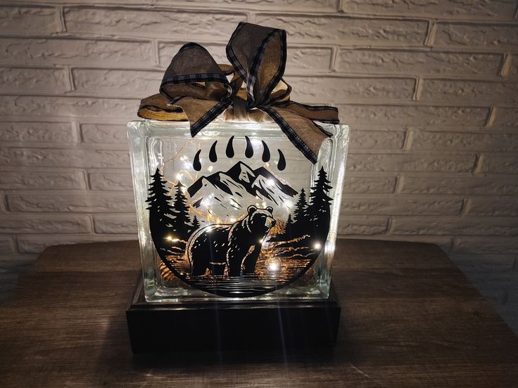 a lighted glass block with an image of a bear in the woods on it's side