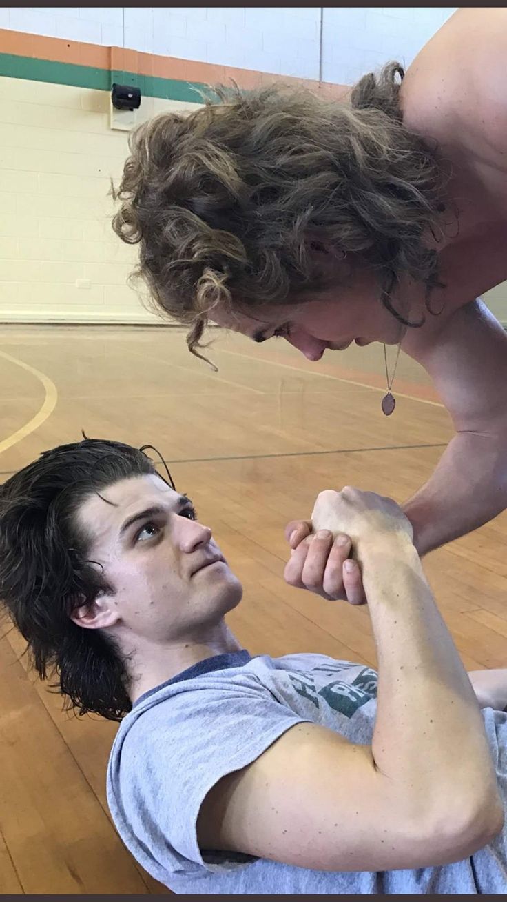 a man is holding another mans arm in the gym while he holds his leg up