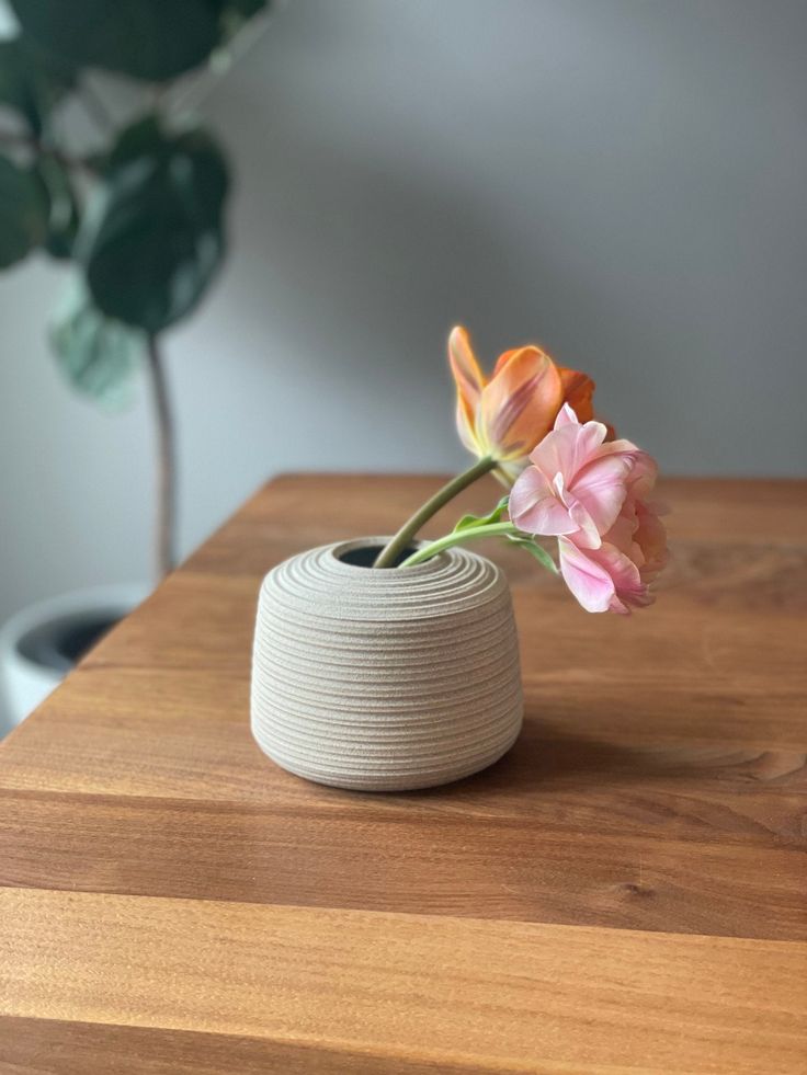 a flower in a vase sitting on top of a wooden table