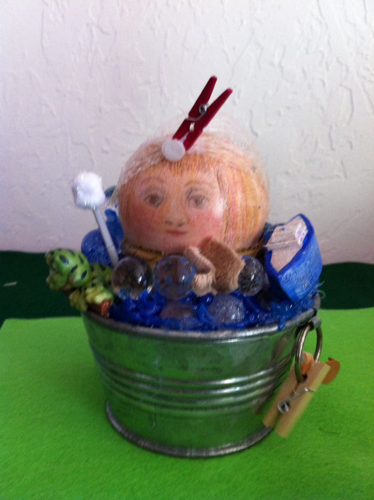 a doll in a bucket with toothbrushes and other items