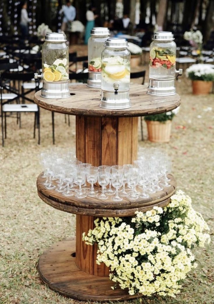 three tiered wooden table with glasses on it and flowers in vases next to them