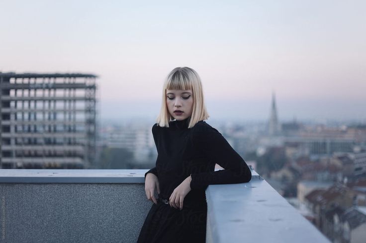 a woman standing on top of a building next to tall buildings