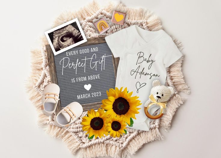 a baby announcement with sunflowers, teddy bear and other items on a blanket