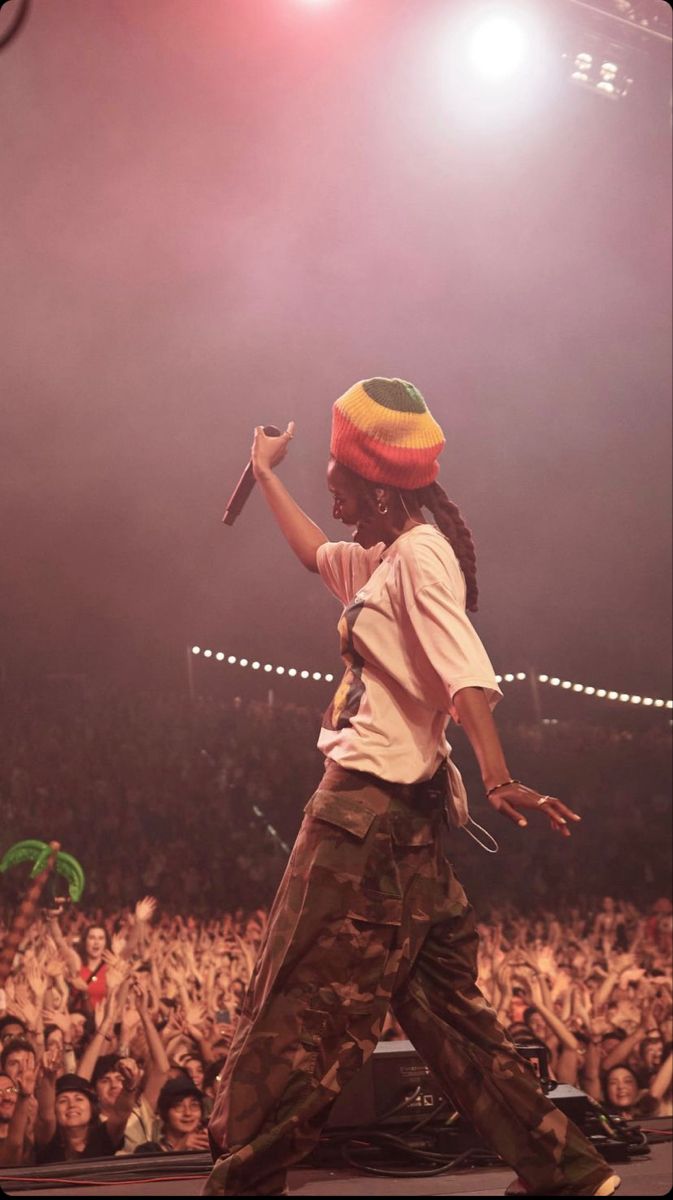 a young man with dreadlocks on his head is performing in front of an audience