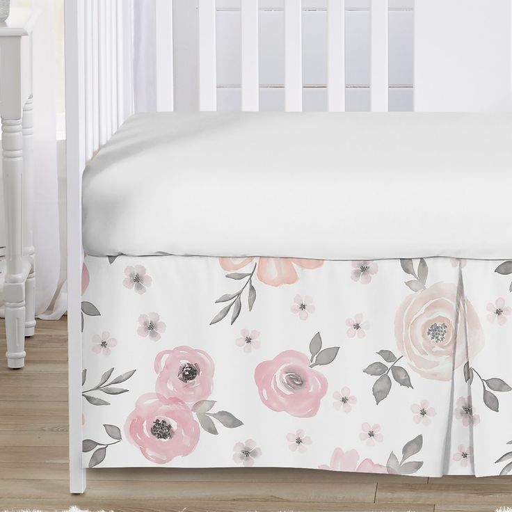 a white crib bed with pink flowers on it