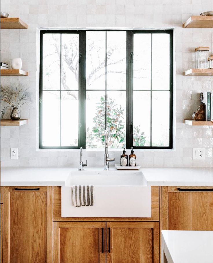 a kitchen with wooden cabinets and white counter tops is pictured in this image, there are open windows above the sink