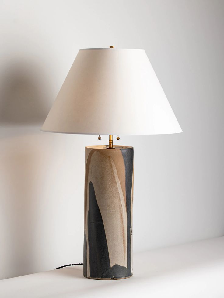 a lamp that is sitting on top of a white table next to a light fixture