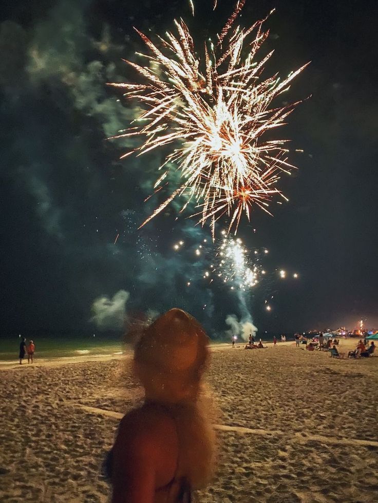 a woman looking at fireworks on the beach