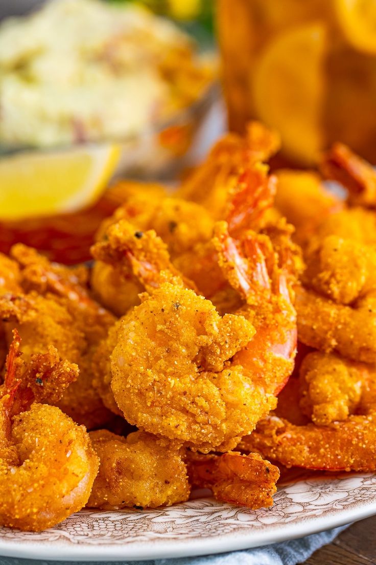 fried shrimp on a plate with lemon wedges