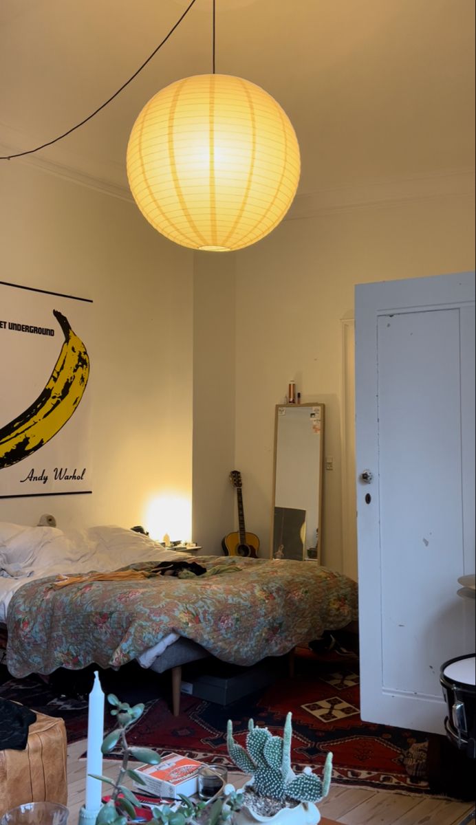 a bedroom with a bed, table and hanging lamp in the corner next to it