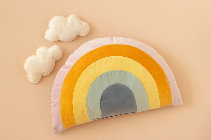 there is a pillow with a rainbow on it next to some cotton balls and a toy