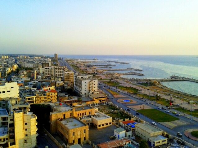 an aerial view of a large city by the ocean with buildings and water in the background