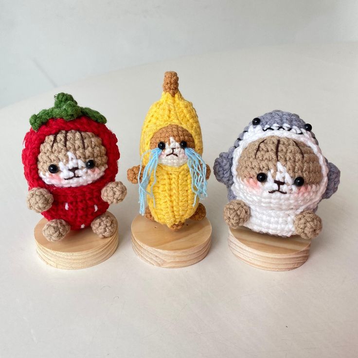 three small crocheted animals sitting on top of wooden bases