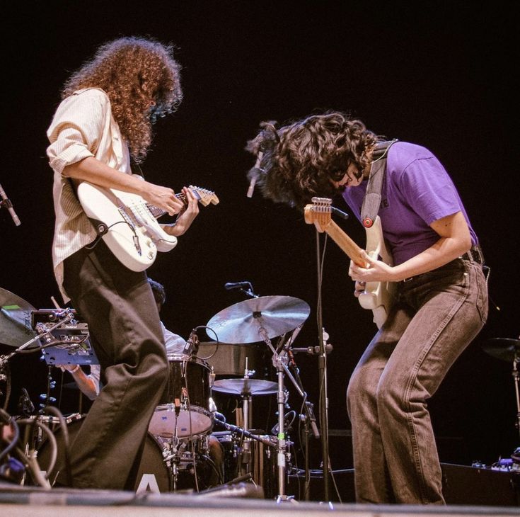 two people on stage with guitars and drums