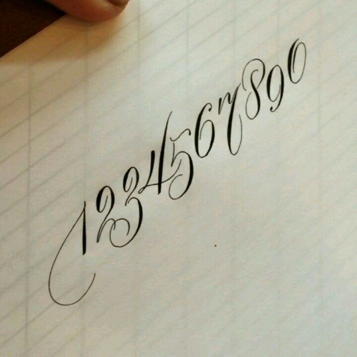 someone is writing on a piece of paper with the numbers in cursive handwriting