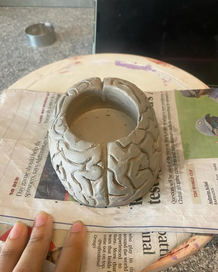 a person is making a vase out of clay on top of a paper with scissors