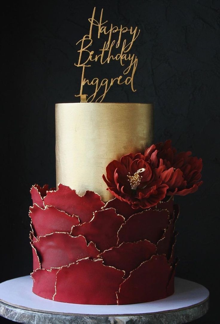 a red and gold birthday cake with a flower on top