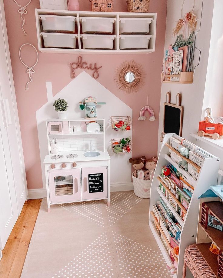 a child's playroom with pink walls and white furniture, including a doll house