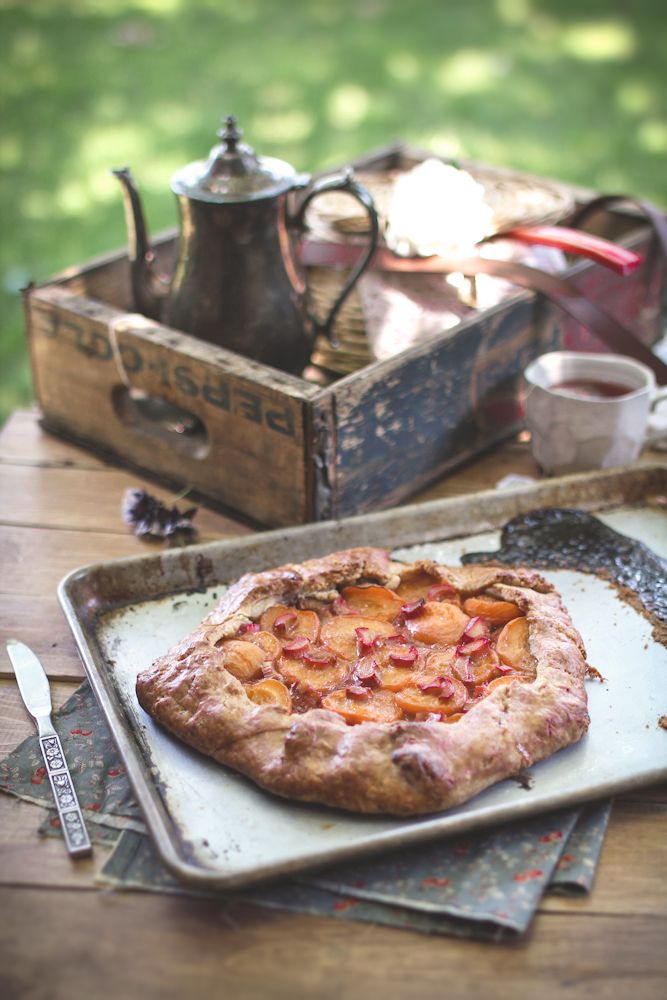 a pizza sitting on top of a metal pan next to a tea pot and spoon