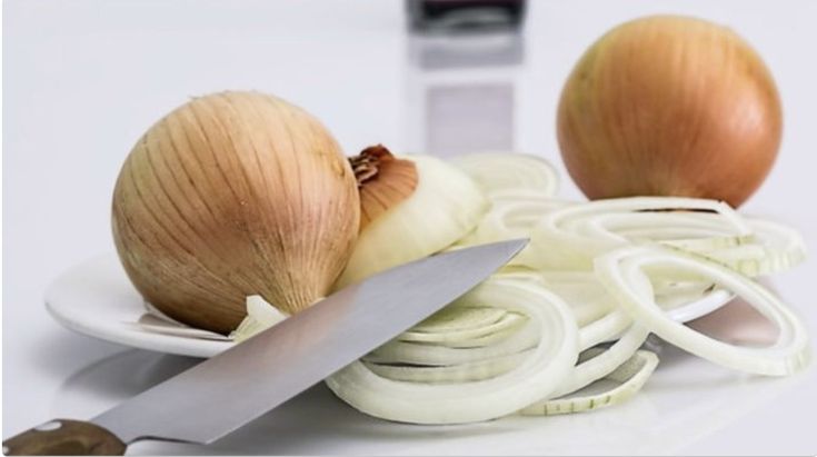 an onion and onions on a white plate with a knife next to the onion slices