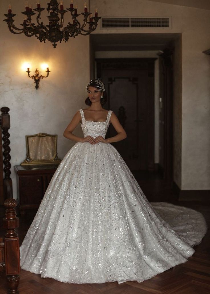 a woman in a white wedding dress standing next to a chandelier