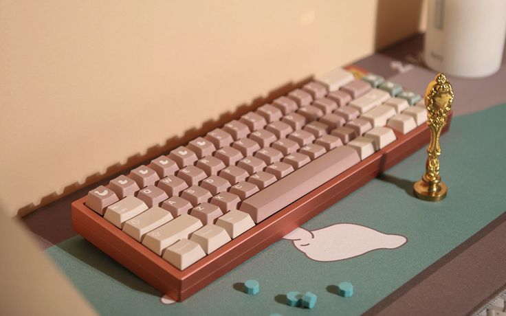 a computer keyboard sitting on top of a desk next to a cup and candle holder