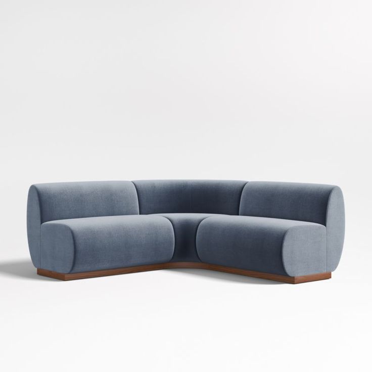 a blue sectional couch sitting on top of a white floor next to a wooden frame