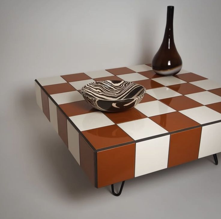 an orange and white checkered coffee table with a vase on the top, next to it