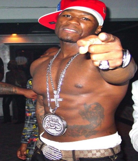 a shirtless man pointing at the camera with his hand on his hip while wearing a red and white hat