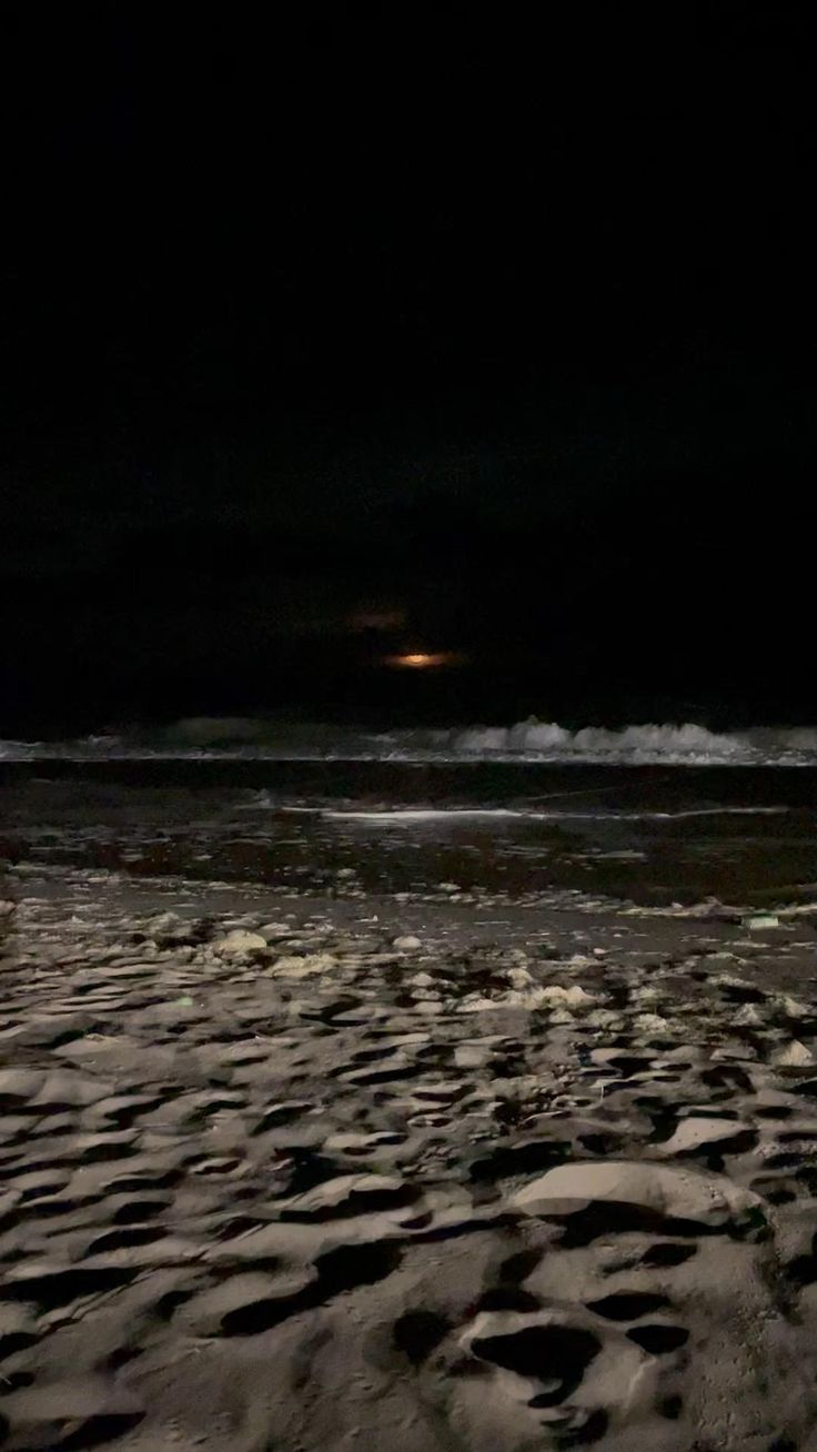 a man standing on top of a sandy beach at night