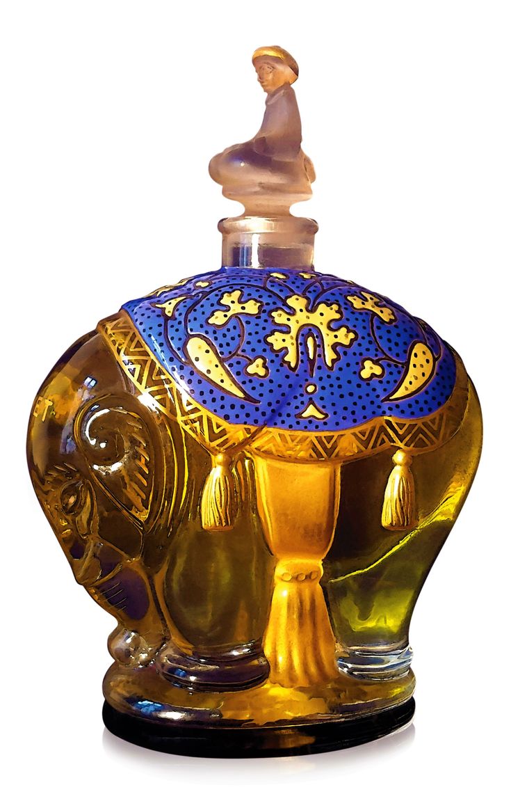 an elephant shaped glass bottle with a gold base and blue design on the top, sitting in front of a white background