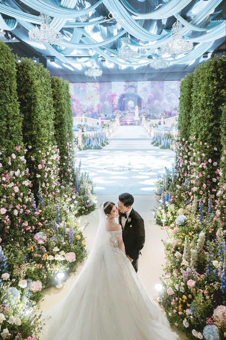 a bride and groom are standing in front of an archway with flowers all around them