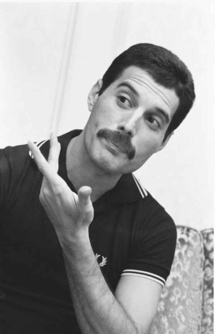 a man with a moustache on his face making the middle finger sign while sitting on a couch