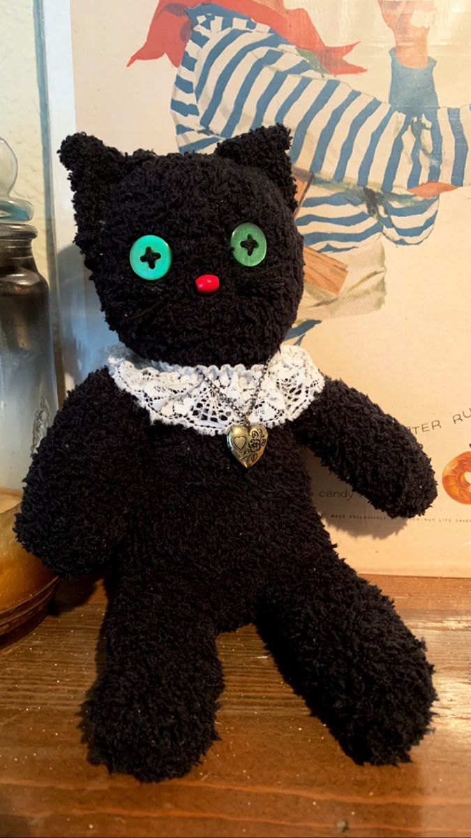 a black teddy bear with green eyes sitting on a table