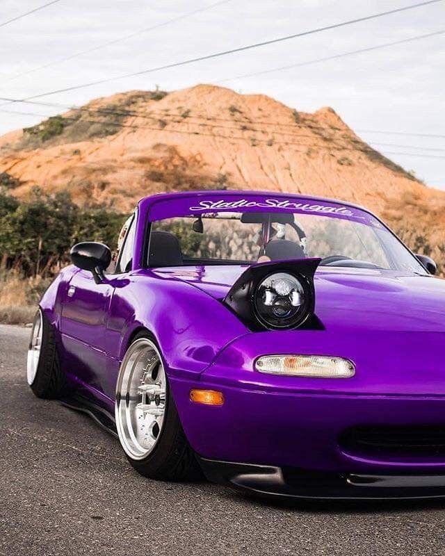 a purple sports car parked in front of a mountain