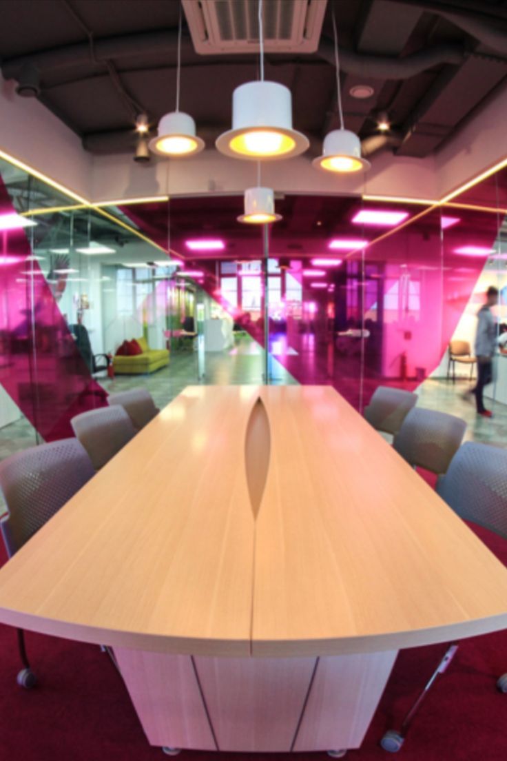 an empty conference room with chairs and a table in front of the glass wall that has pink lights on it